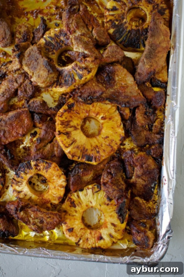 Authentic Al Pastor Tacos 6 Perfectly roasted marinated pork and caramelized pineapple slices on a sheet pan, just out of the broiler.