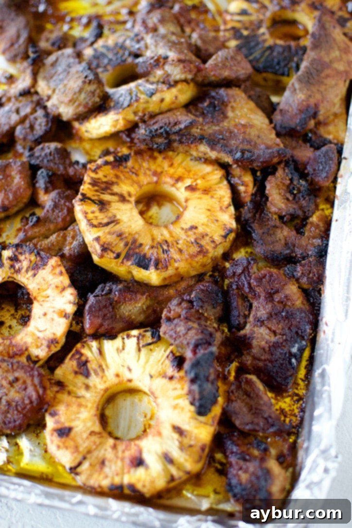 Authentic Al Pastor Tacos 10 Marinated pork and cut pineapple on a baking sheet, after being perfectly roasted.