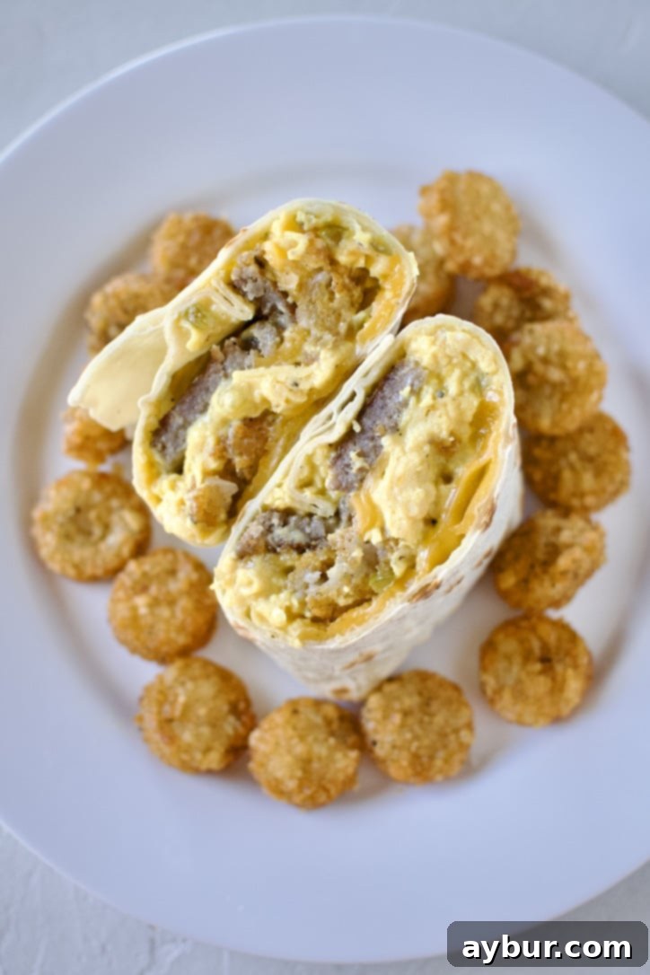 Homemade Breakfast Burrito all rolled up on a plate, and cut in half, next to a pile of extra hash browns.