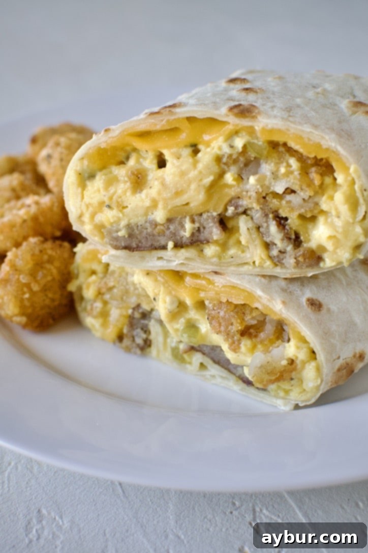 Homemade Breakfast Burrito all rolled up on a plate, and cut in half, next to a pile of extra hash browns.