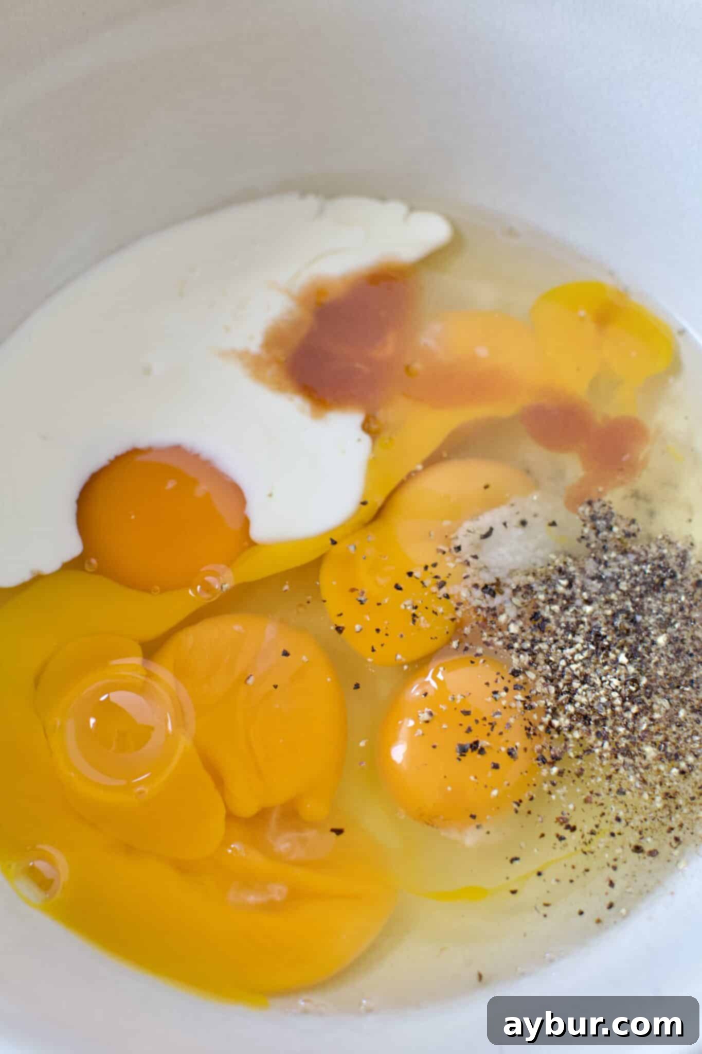 Eggs, Cream, hot sauce, salt, and pepper in a bowl ready to whipped up.