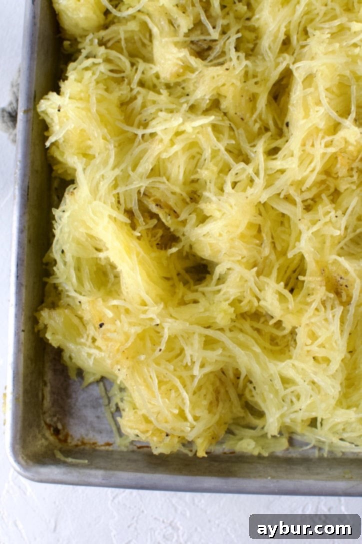 Roasted spaghetti squash after being scraped from the skin, forming distinct, delicate spaghetti-like strands.