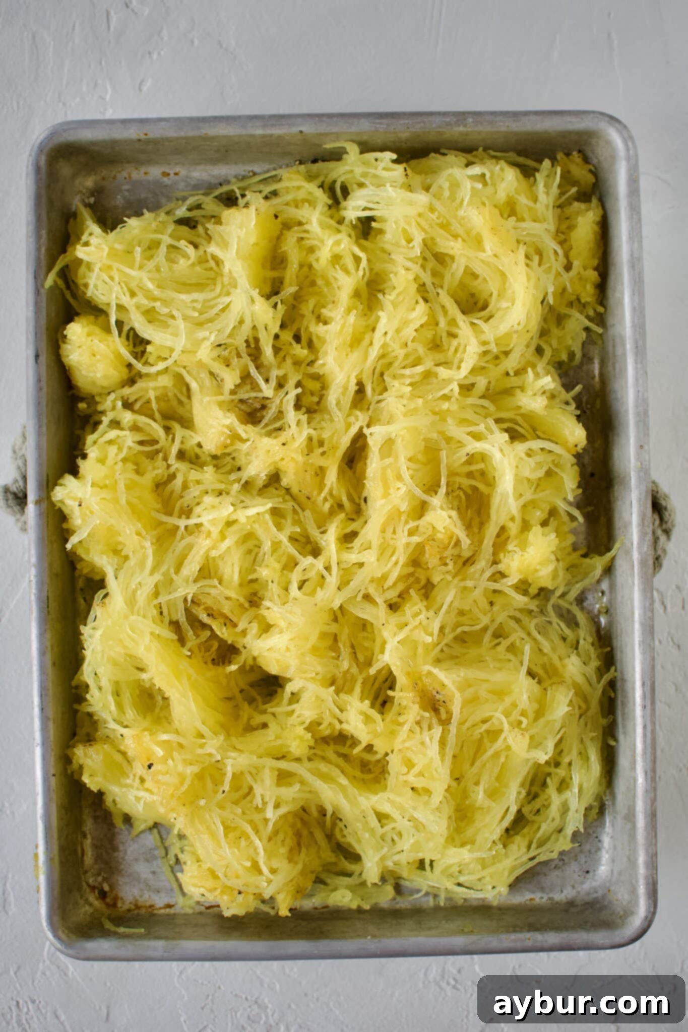 A vibrant, close-up shot of roasted spaghetti squash, beautifully scraped into delicate strands, ready for serving.