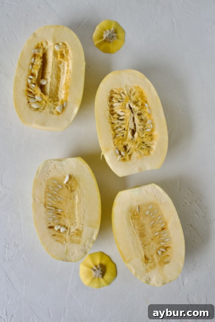 A spaghetti squash meticulously split in half lengthwise, revealing its inner cavity and seeds.