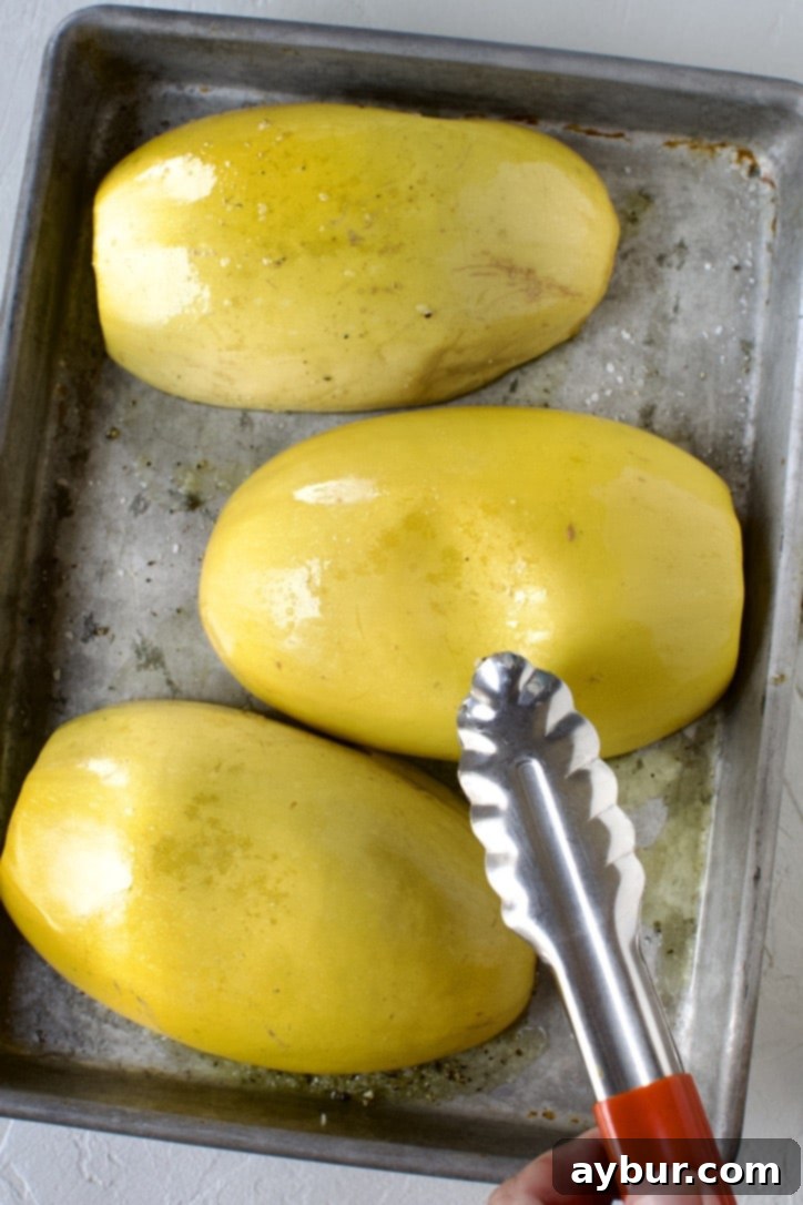 Cooked spaghetti squash being tested for doneness by gently pressing on its skin, showing a clear indentation indicating it's perfectly roasted.