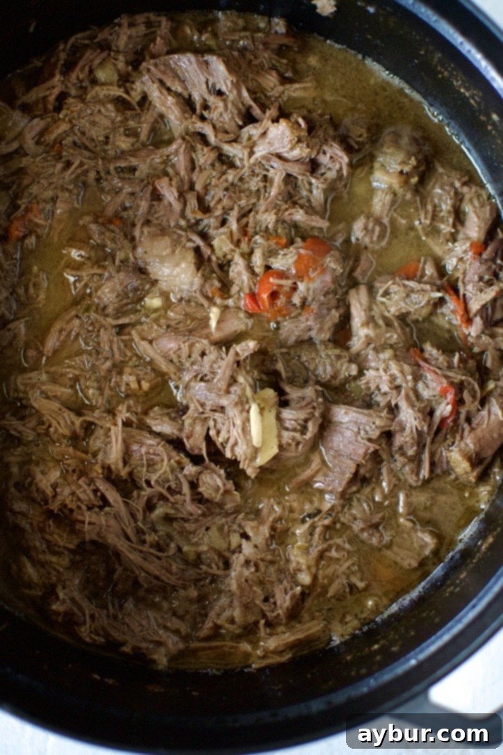 Shredded Italian Beef fully submerged back into the rich, aromatic juices in the pot, ready for serving.