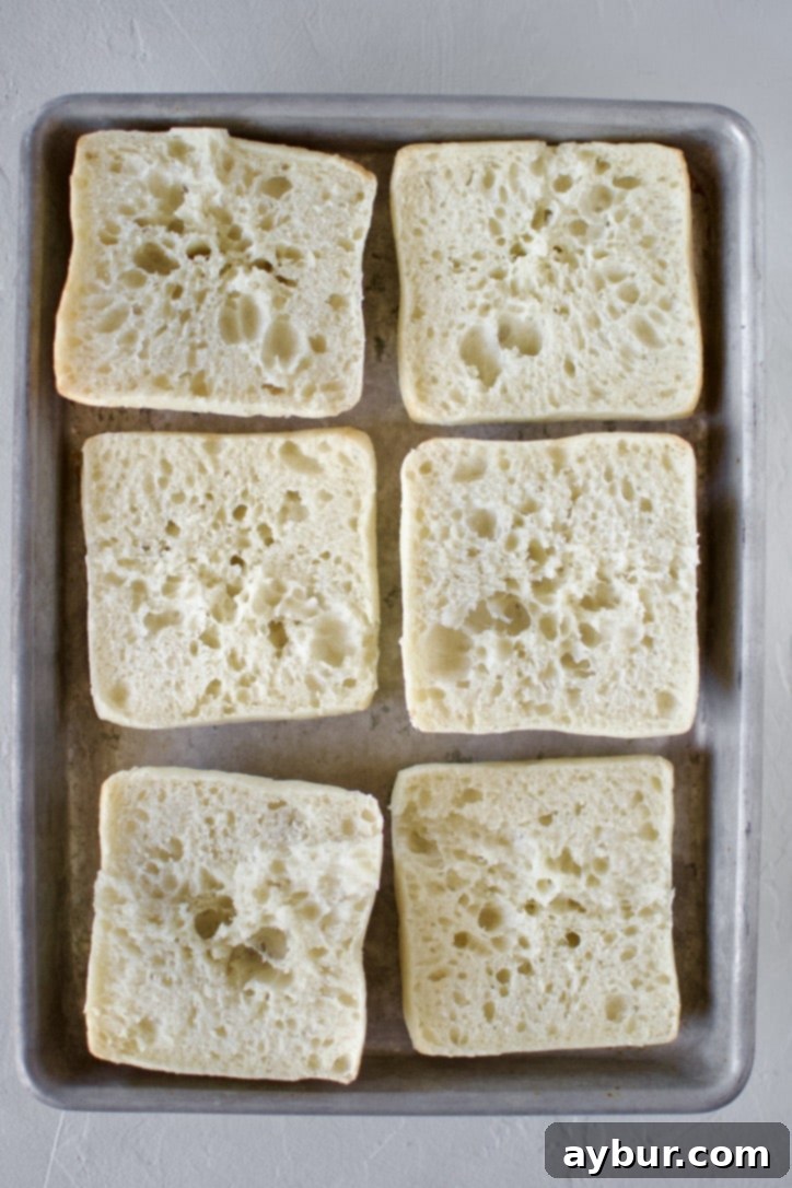 Ciabatta rolls split open on a sheet tray, exposing the soft interior.