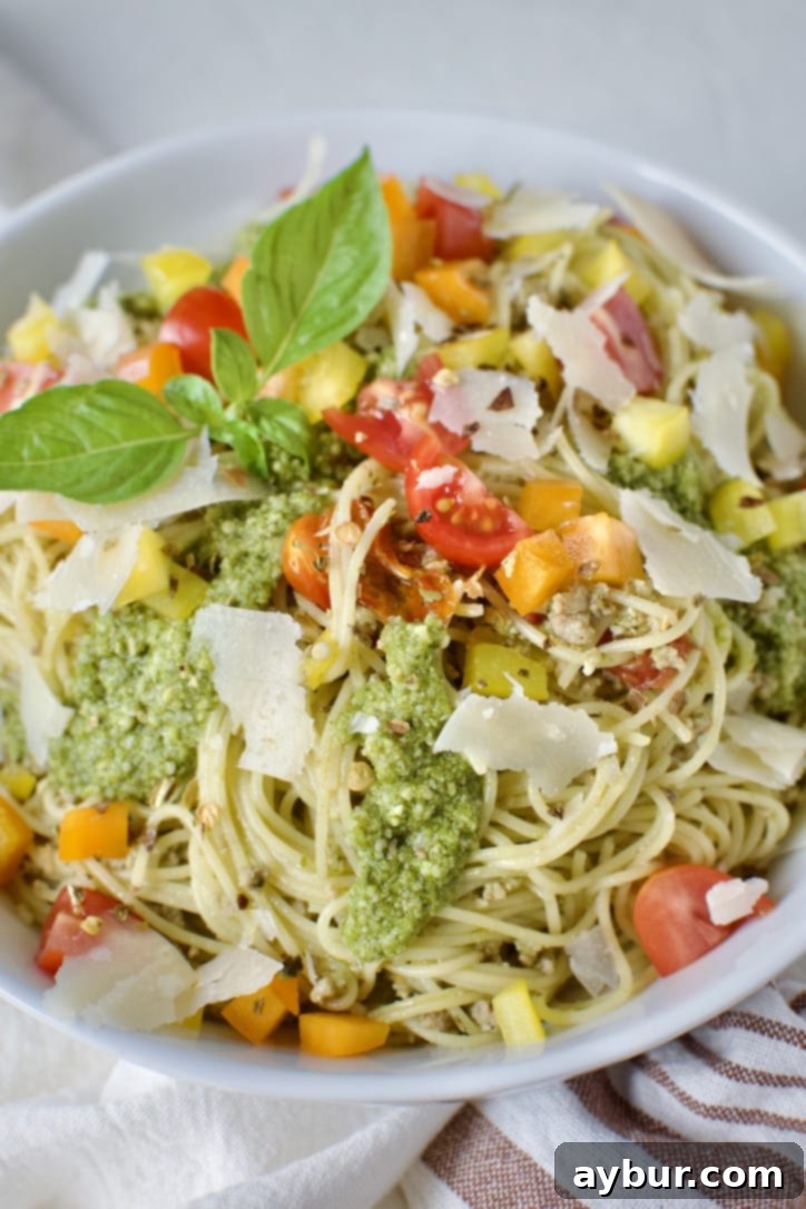 A vibrant bowl of Pesto Spaghetti, topped with fresh parmesan, ready to be enjoyed.