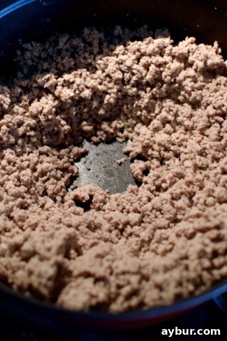 Close-up of browned ground turkey in a large pot after draining excess liquid, showing a leaner base.