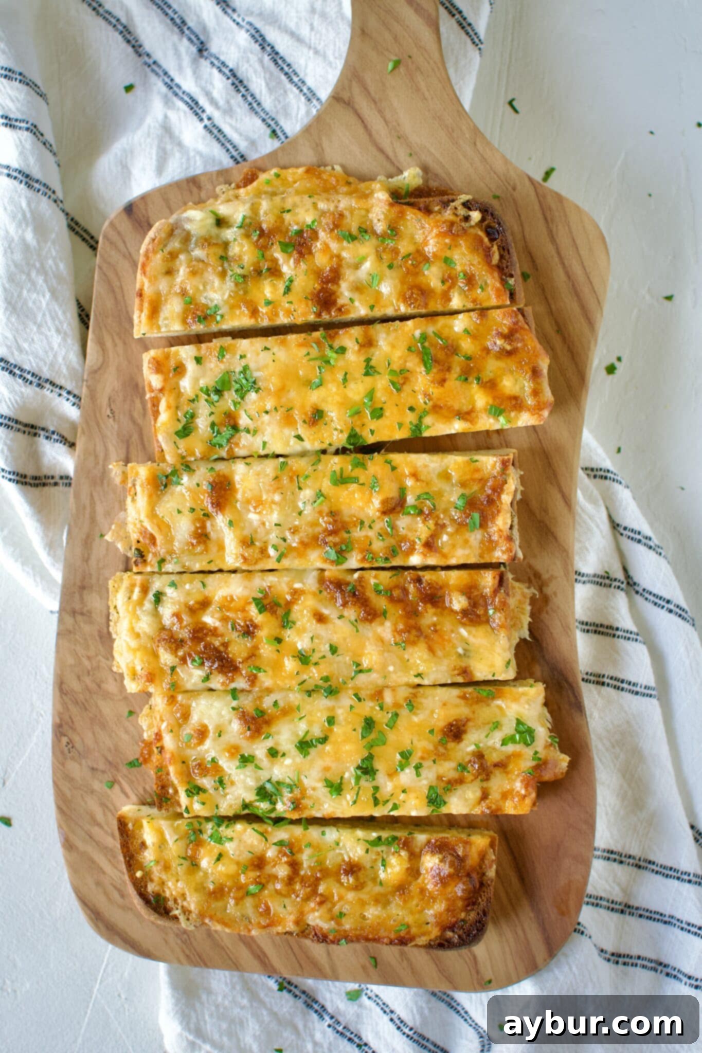 Individual slices of hot Cheesy Garlic Bread arranged on a platter, ready to be picked up and savored.