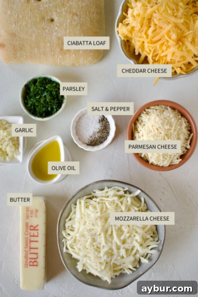 A selection of fresh ingredients including ciabatta bread, butter, minced garlic, olive oil, salt, pepper, and three types of cheese, laid out for making Cheesy Garlic Bread.