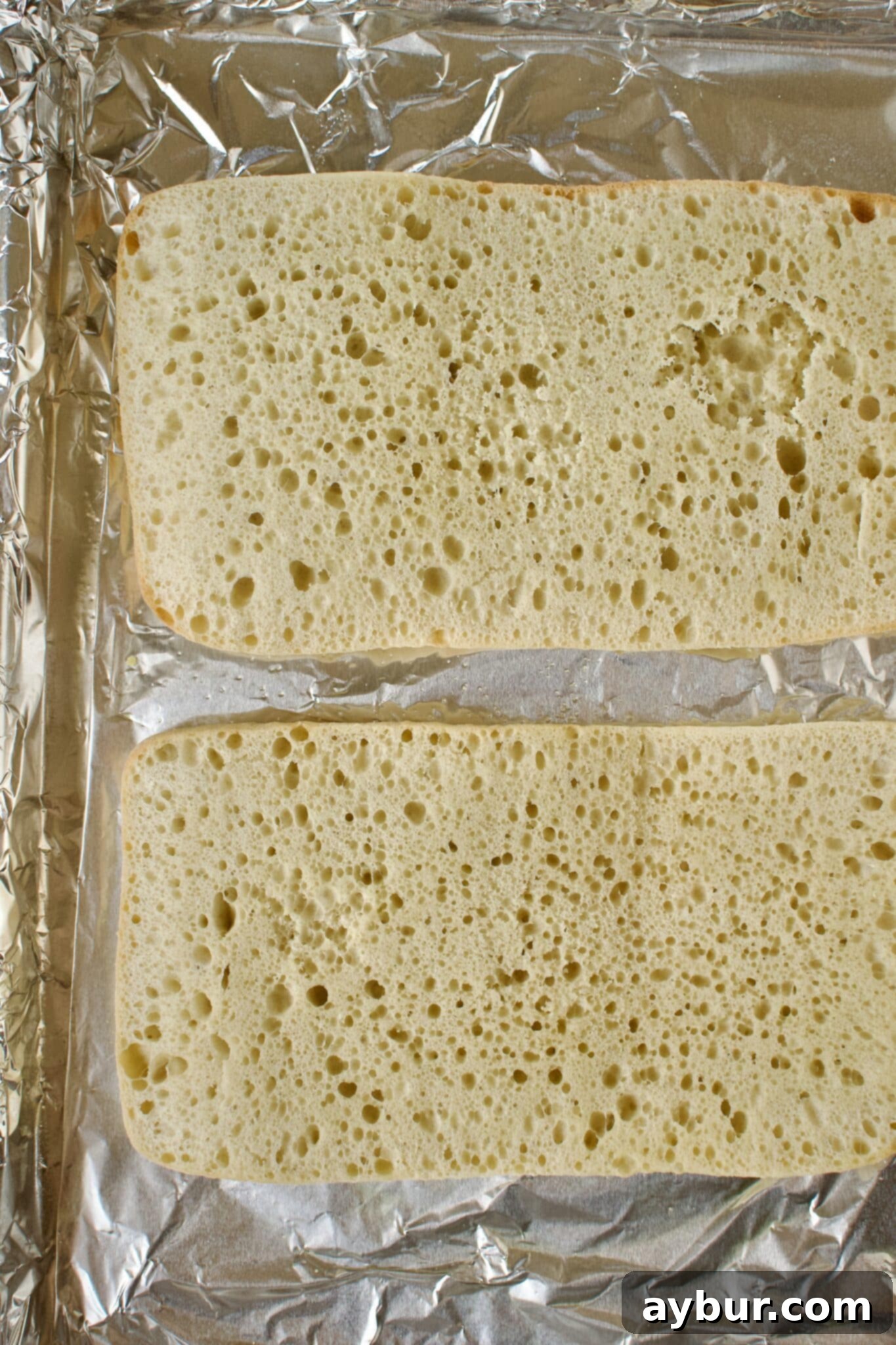 A ciabatta loaf expertly sliced lengthwise down the middle, ready to receive its flavorful toppings.