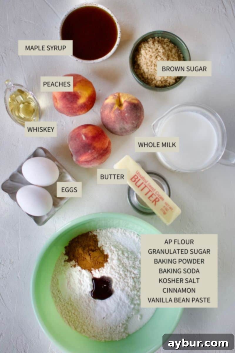 Golden Peach Pancakes 3 A collection of fresh ingredients laid out on a countertop, including flour, milk, eggs, cinnamon, baking powder, ripe peaches, and a bottle of whiskey, essential for making delicious Peach Pancakes.