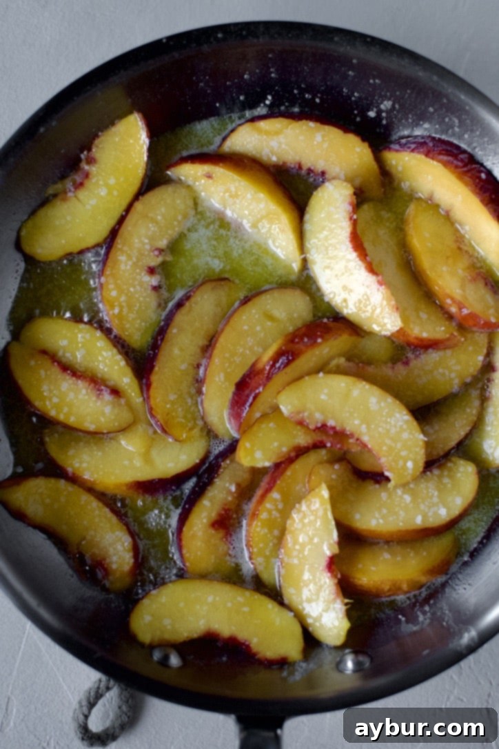 Golden Peach Pancakes 8 Fresh peach slices gently sautéing in melted butter with a sprinkle of salt in a skillet, beginning to soften and release their natural sweetness.