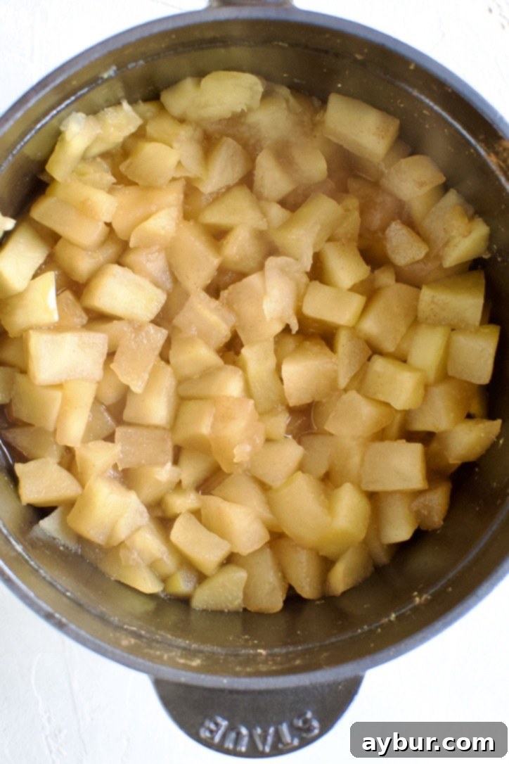Soft, cooked apples resting at the bottom of a pot, prior to being mashed into sauce.