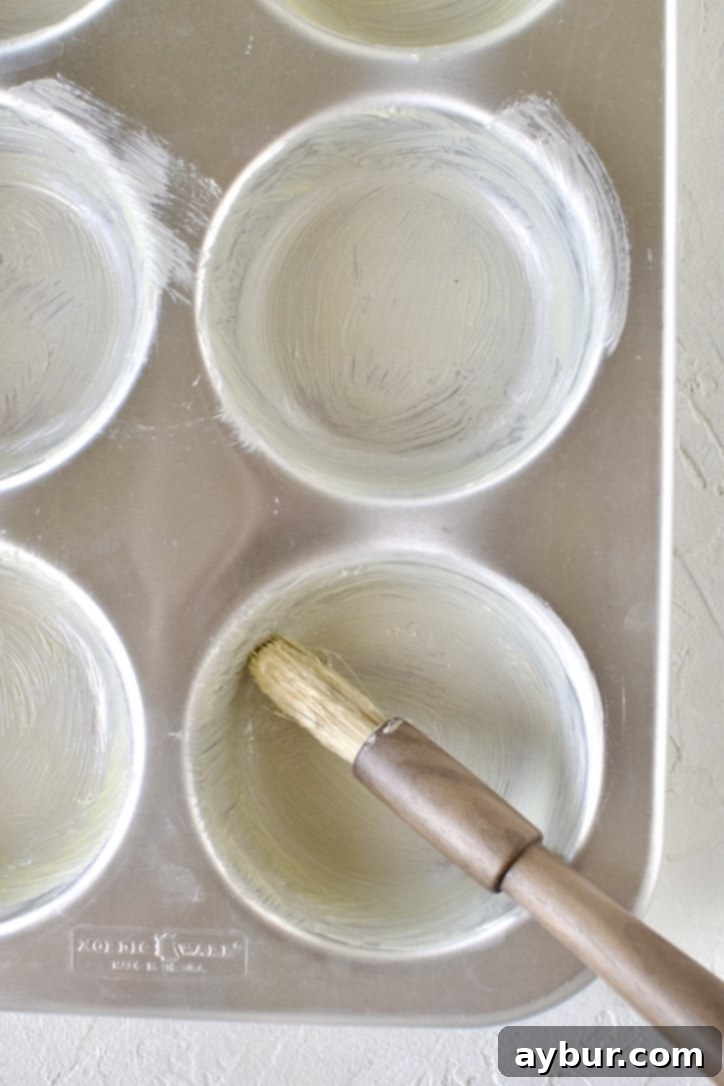 Golden Apple Crumb Muffins 4 Buttering a jumbo muffin tin.