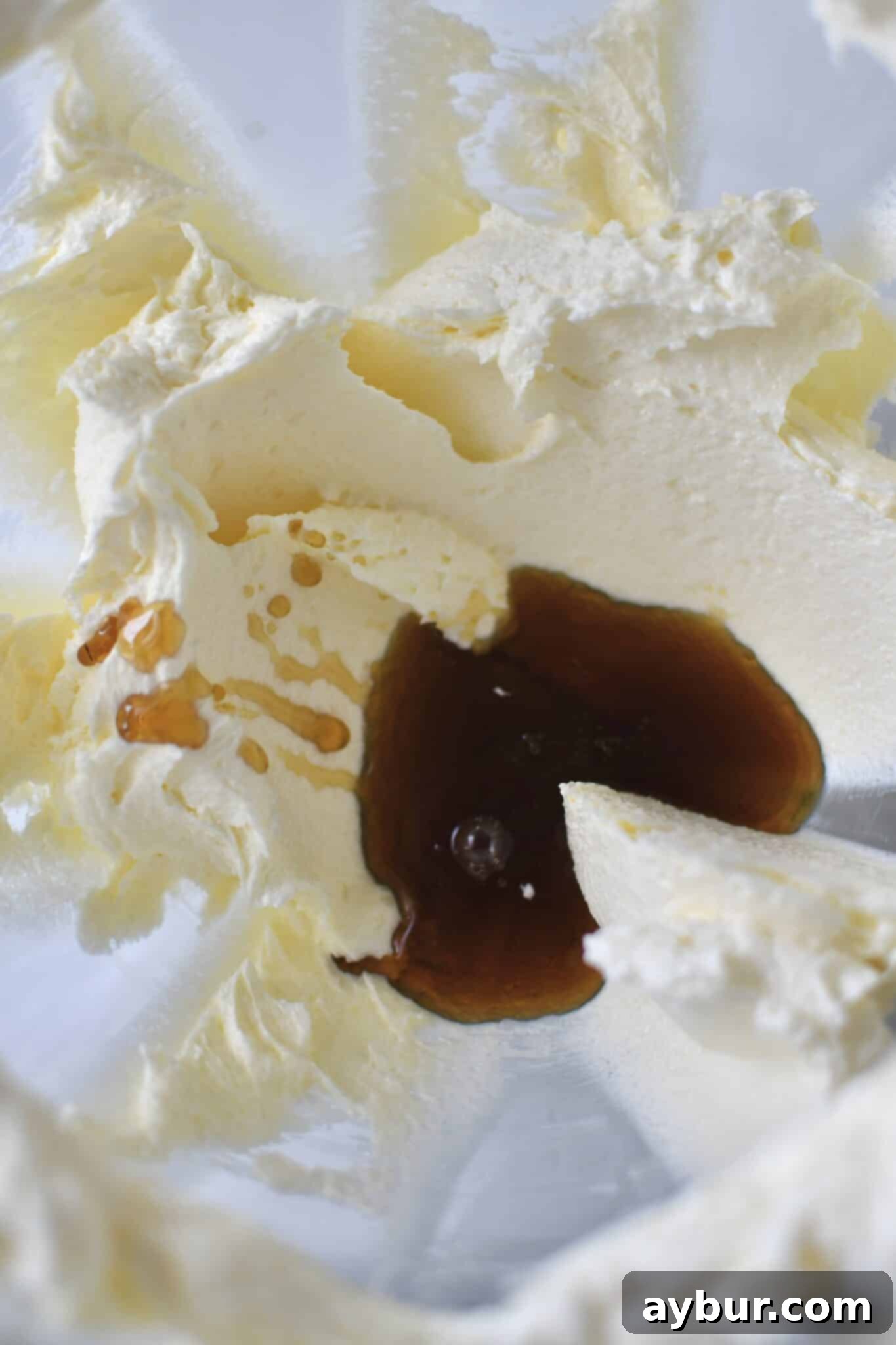 Pouring rich, amber maple syrup into the creamed butter and sugar mixture.