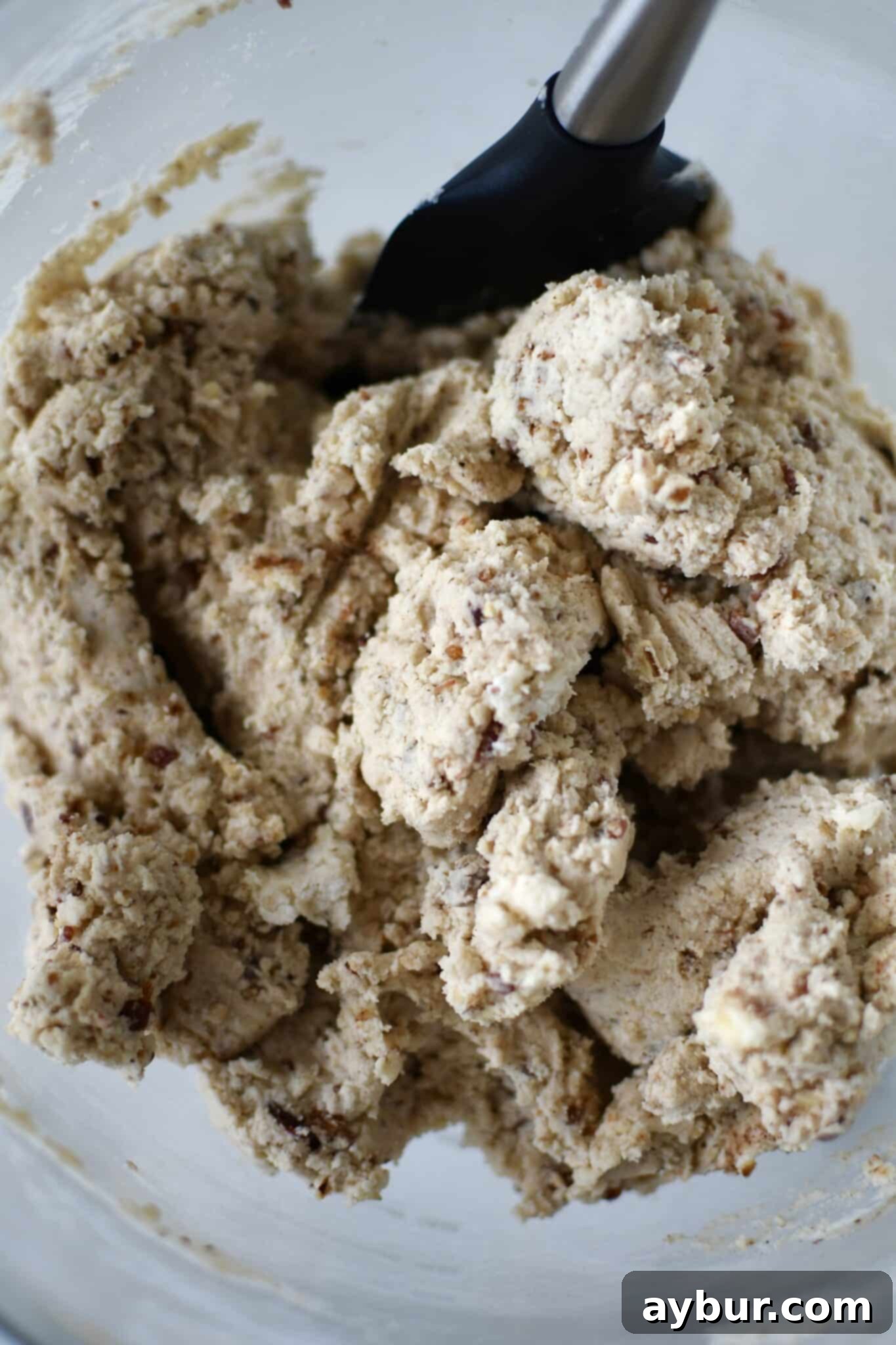 Perfectly mixed cookie dough with visible pecan and bacon flecks in the mixing bowl.