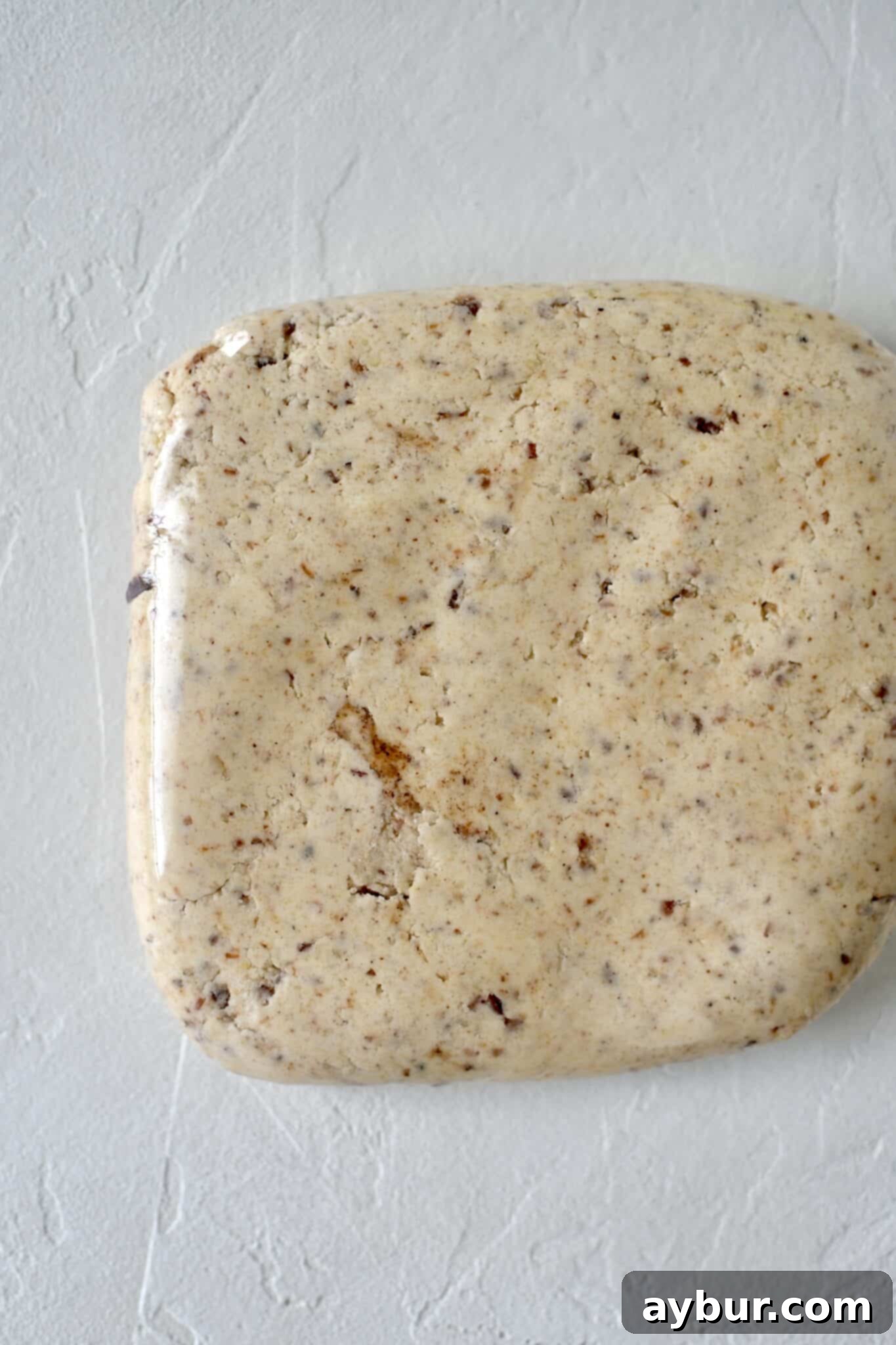 A disk of cookie dough, tightly wrapped in plastic, chilling in the refrigerator.