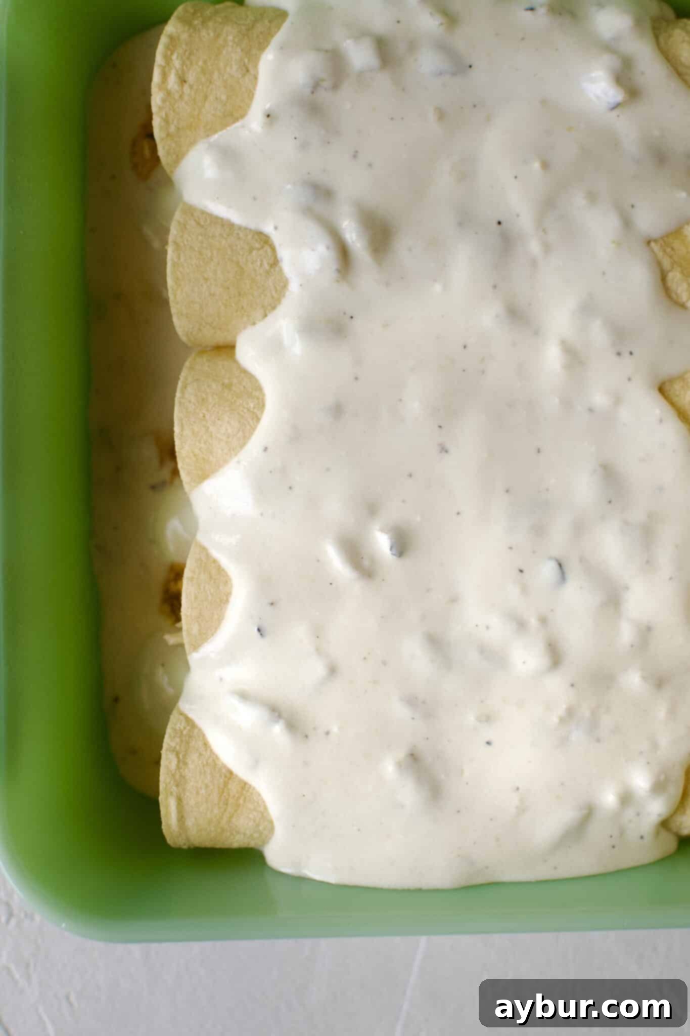 Chicken filled tortillas rolled up and placed in a baking dish that has been lined with sour cream enchilada sauce. Then topped with more sauce.