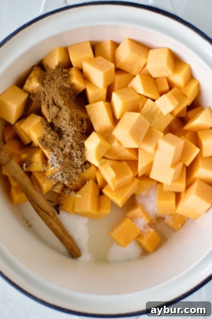 Raw pumpkin pieces, sugar, lemon juice, and spices are mixed together in a saucepan, ready for cooking.