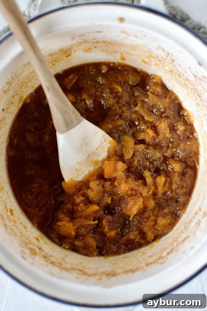 Fully cooked pumpkin jam in a saucepan, before being mashed, showing soft, translucent pumpkin pieces.