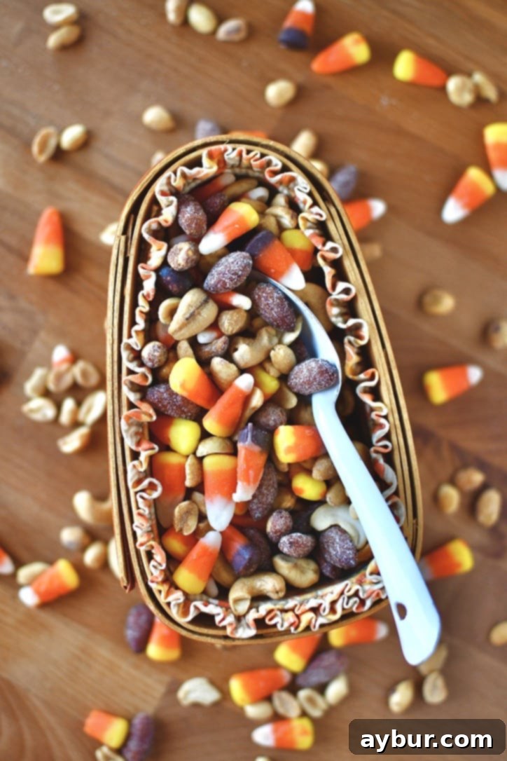 A large bowl filled with candy corn and various peanuts, ready to be mixed for a fall snack.