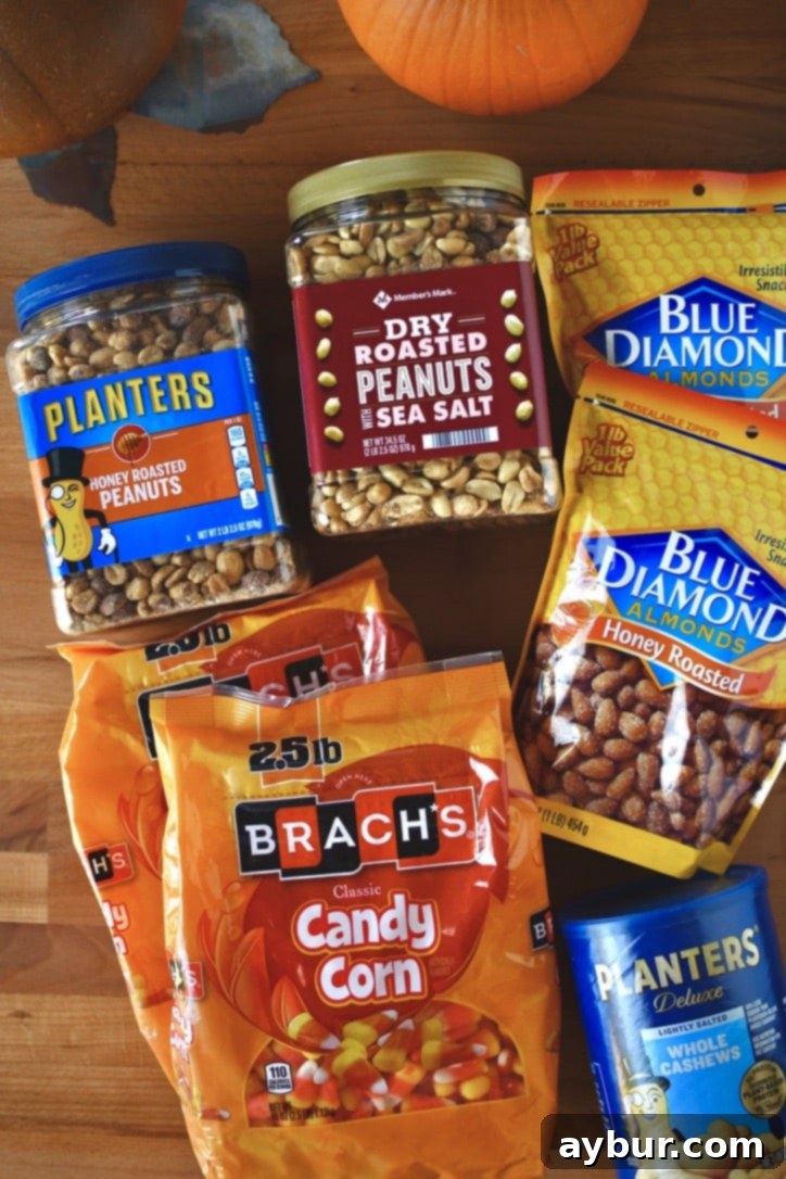 Various bags and containers of candy corn, peanuts, almonds, and cashews laid out before mixing.