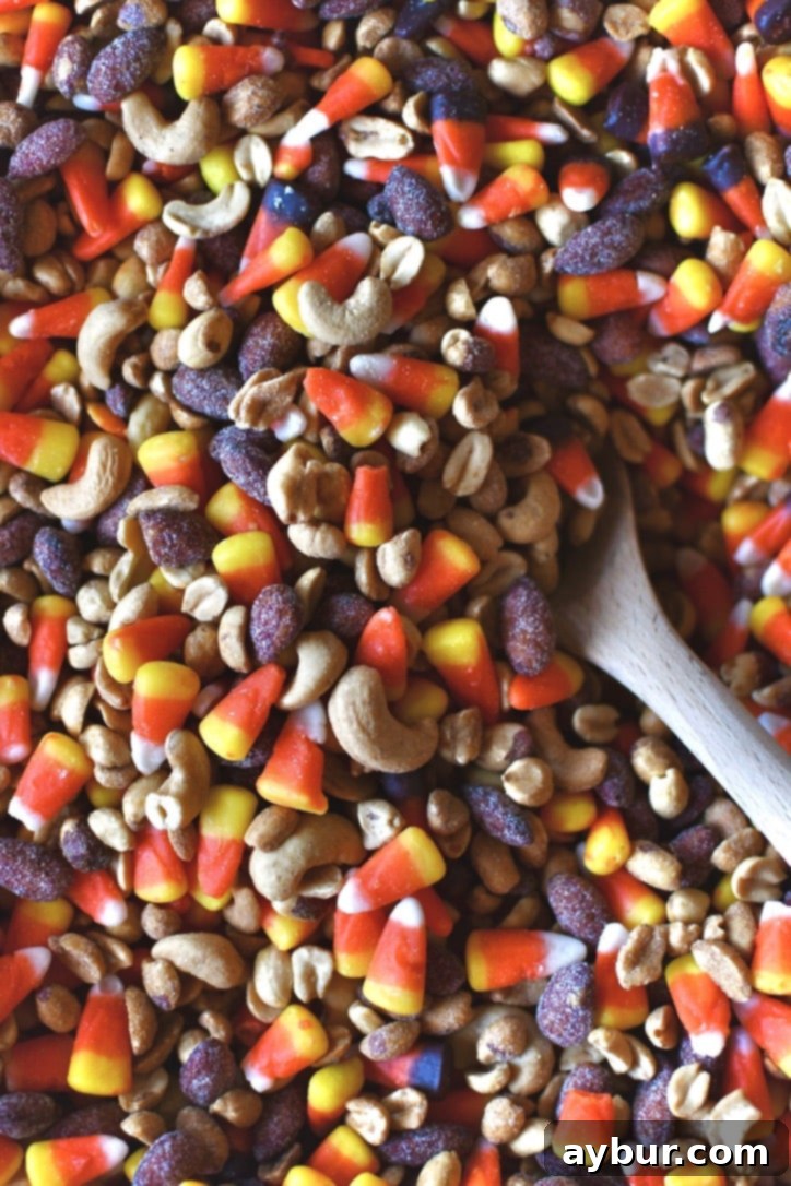 Hands stirring the candy corn and nuts together in the large bowl.