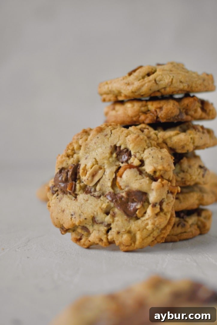 Stacked brown butter kitchen sink cookies with one broken in half to show the delicious mix-ins.