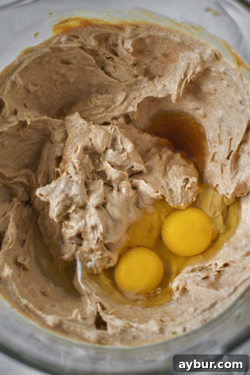 Adding the eggs to the creamed butters and sugars.