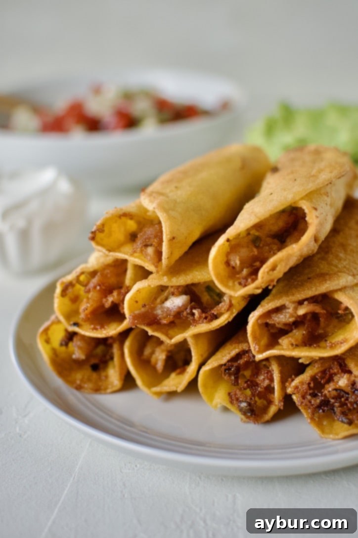 Cooked flautas stacked up on a plate cooling.