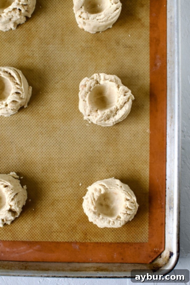 Peanut Butter Jelly Dream Cookies 8 Portioned cookies on a sheet pan with an indent made in them.