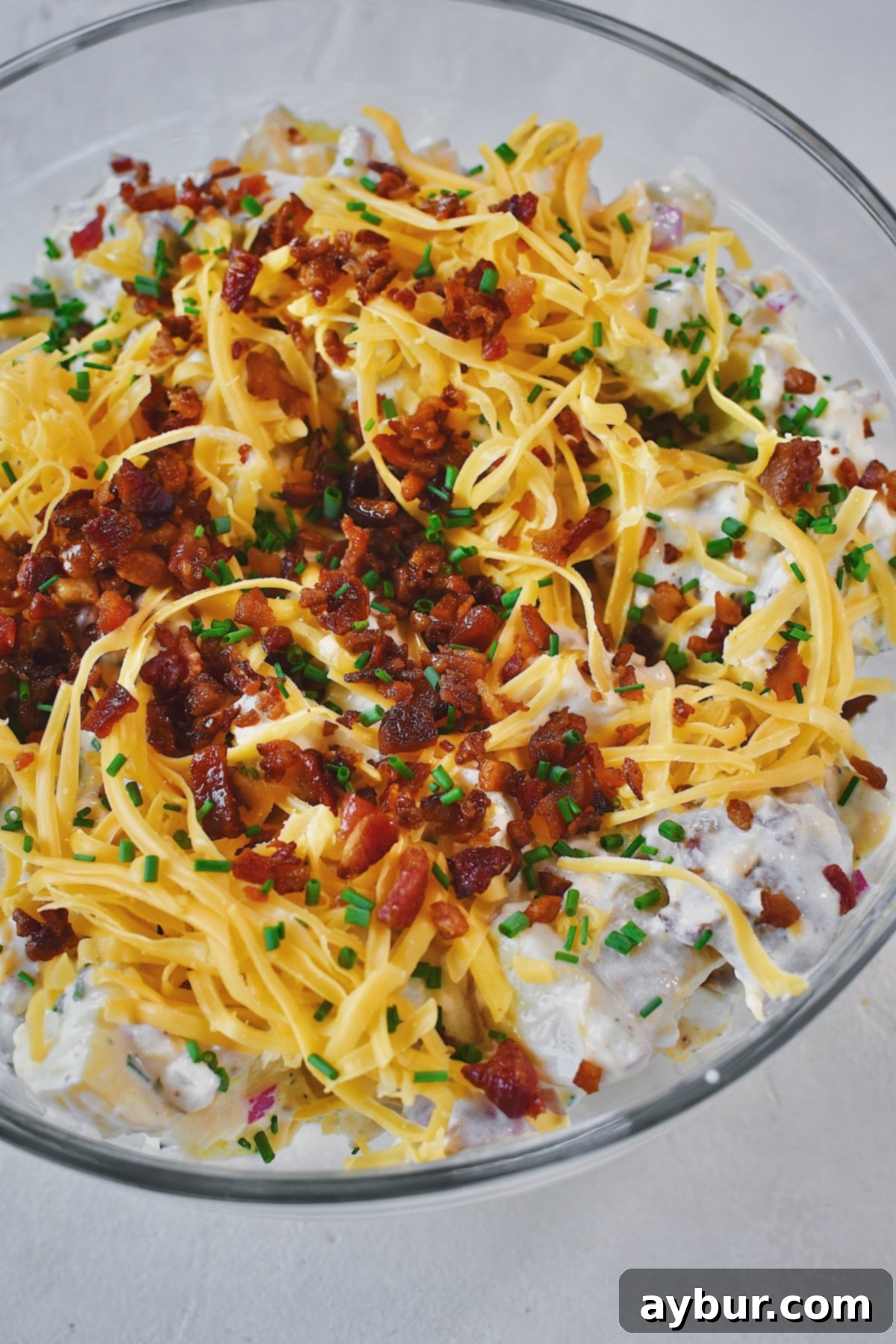 Ranch Potato Salad in a bowl topped with chives, bacon, and cheddar. Ready to serve.