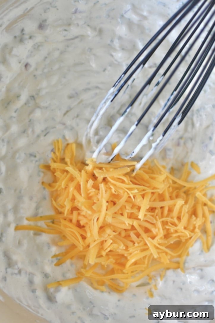 Folding in some of the cheddar with the sauce for the potato salad.