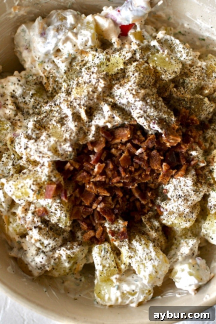 Mixing in some bacon and seasoning along with the potatoes to finish the salad.