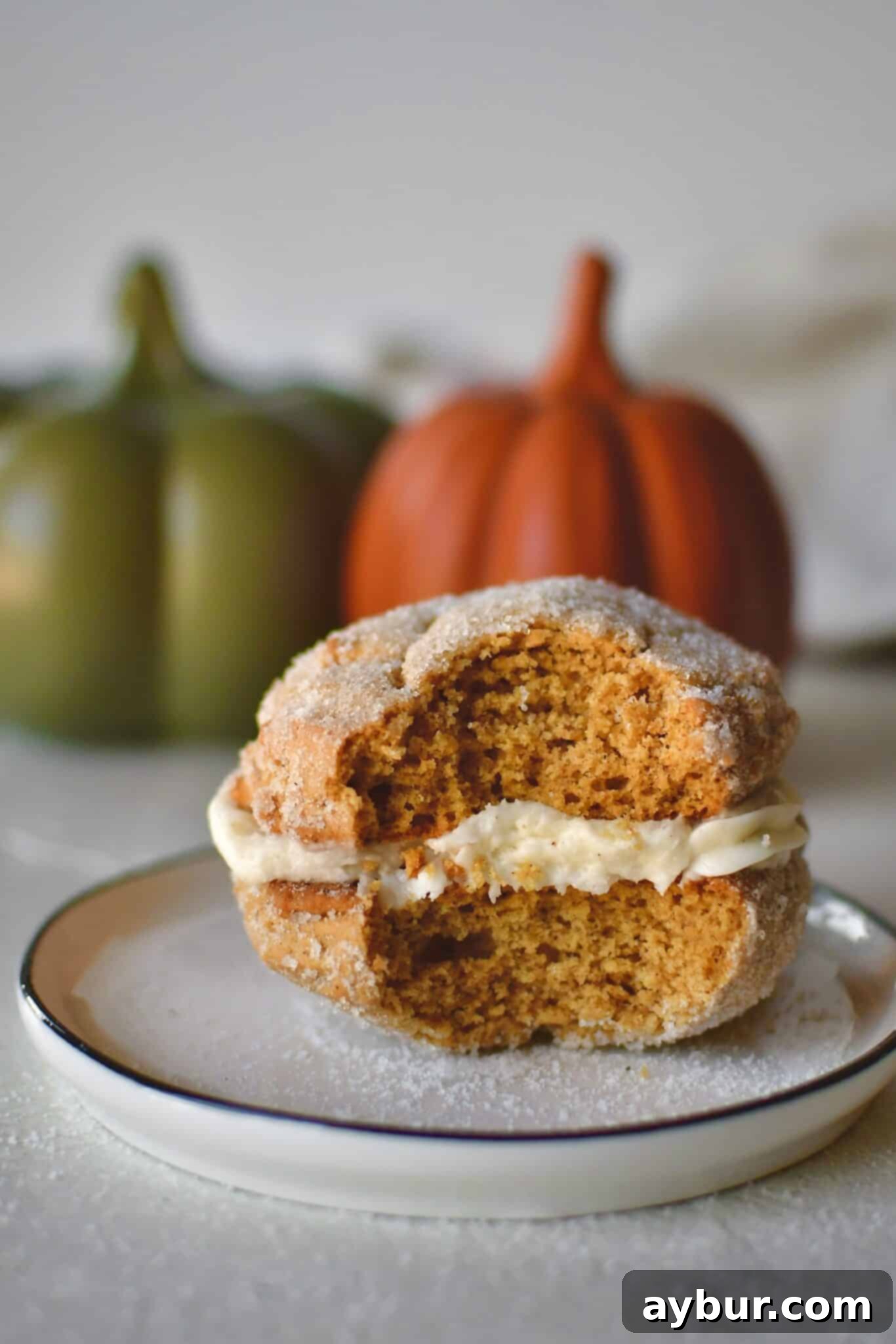 A Pumpkin Whoopie Pie on a plate with a bite taken out of it.