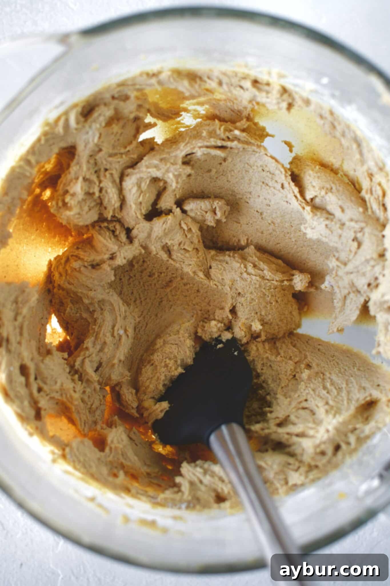 Dry ingredients, including flour and spices, fully incorporated into the pumpkin batter in a stand mixer.