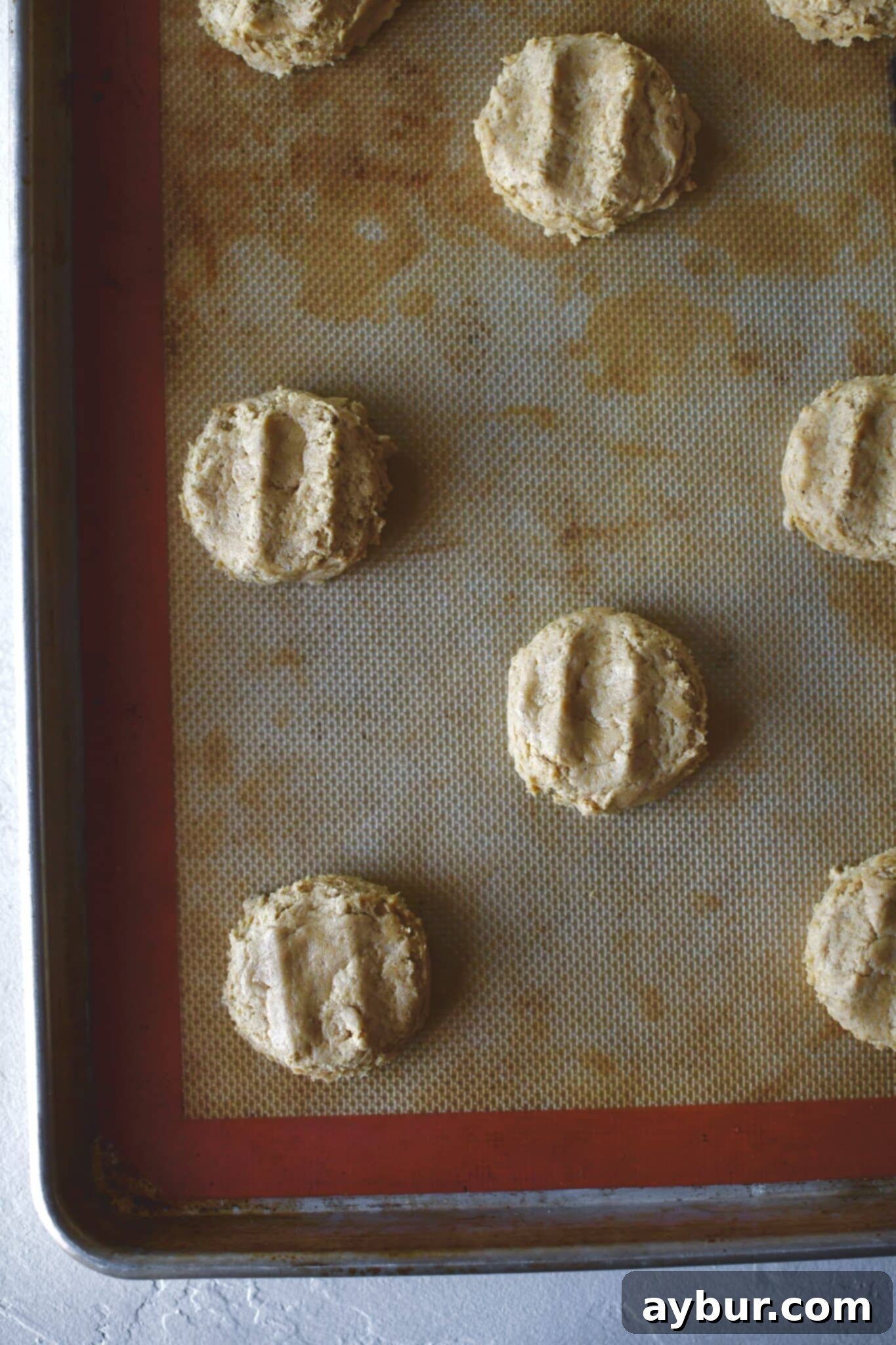 Pumpkin whoopie pie batter neatly portioned and lightly flattened on a parchment-lined baking sheet, ready for baking.