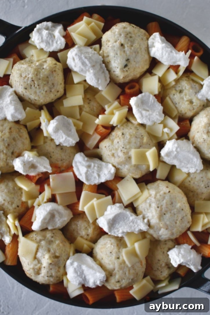 Flavorful Parmesan Chicken Meatballs 11 Diced provolone cheese being spread generously over meatballs and pasta before final bake.