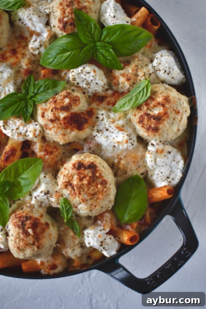 Parmesan Chicken Meatballs with pasta in a skillet, ready to serve.