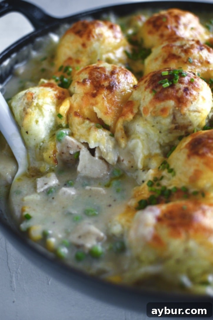 Golden Chicken Mash Bake 2 Finished Chicken Shepherd's Pie just out of the oven, serving a portion out of the pan with a big spoon. Golden brown mashed potatoes with melted cheese on top, with a rich, bubbling chicken and vegetable filling visible.