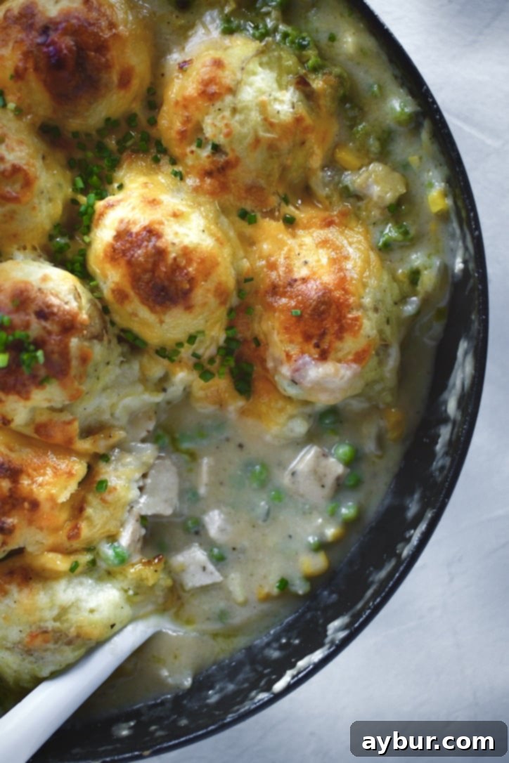 Golden Chicken Mash Bake 14 Finished Chicken Shepherd's Pie just out of the oven, serving a portion out of the pan with a big spoon.