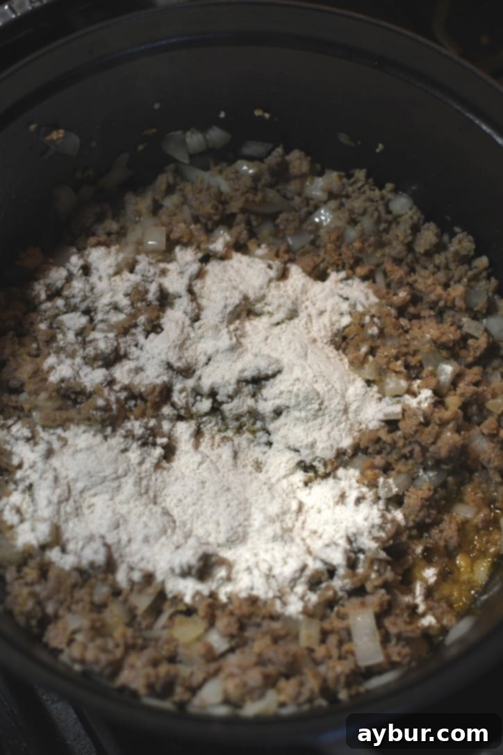 Placing the flour in the pot to form a roux in the fat of the sausage.