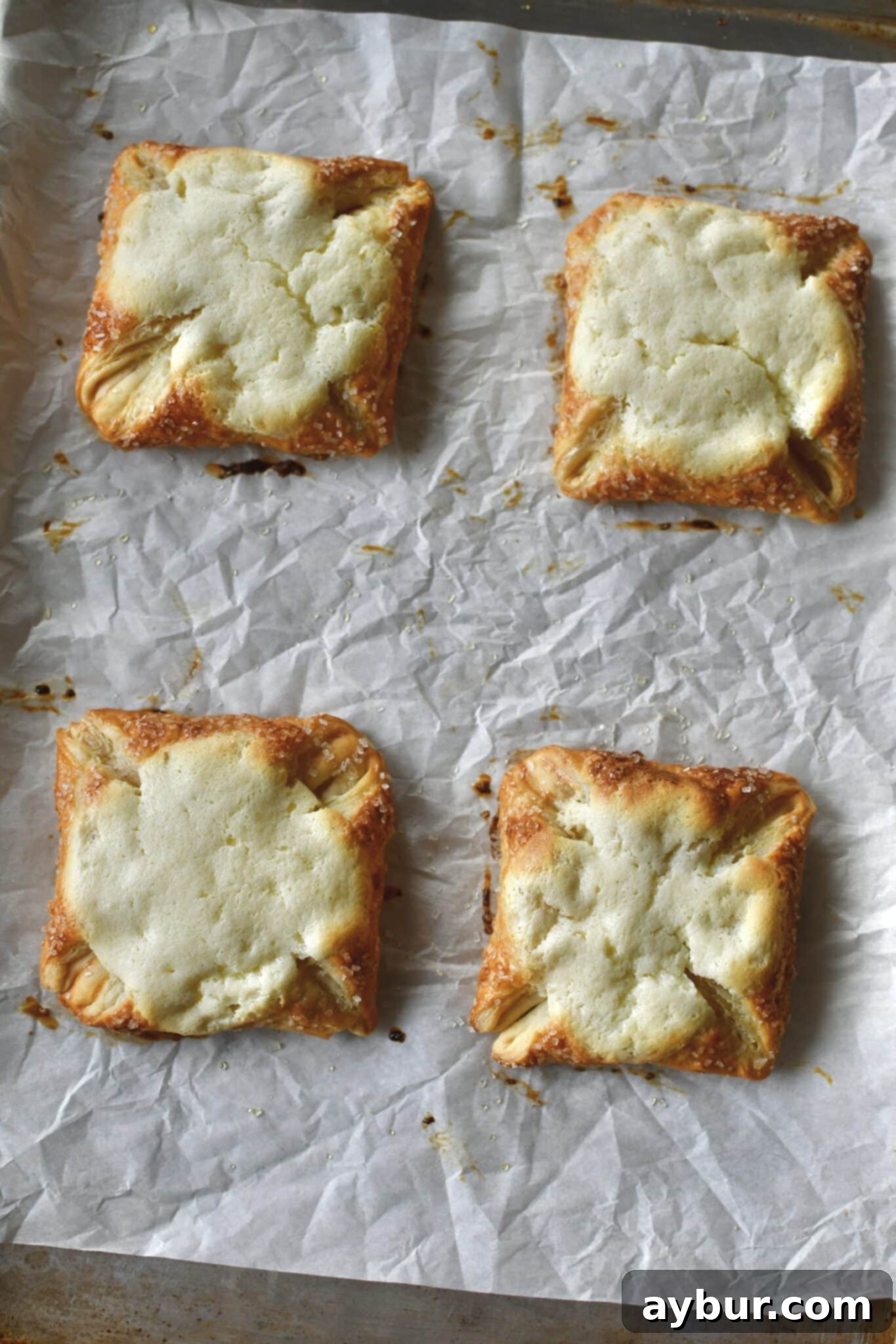 Golden brown danishes freshly out of the oven, puffed and ready for the final touch of plum jam to be added to their centers.