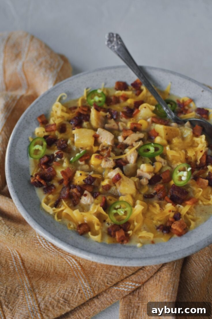 A hearty bowl of creamy chicken corn chowder, topped with crispy bacon and cheese.