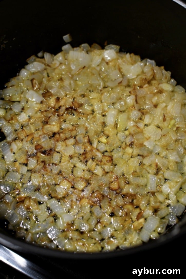 Onions being gently sautéed in melted butter in a large pot, turning translucent and slightly golden.