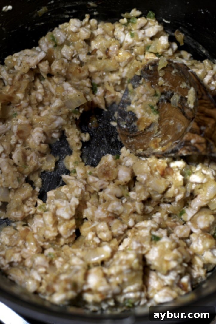 The roux, made from flour and butter, cooking in the pot, ensuring no raw flour taste and creating a thickening base.