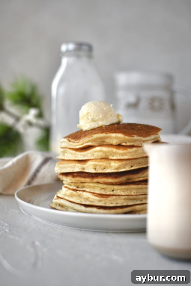 Festive Eggnog Pancakes 2 A stack of fluffy Eggnog Pancakes drizzled with maple syrup, ready to be enjoyed.