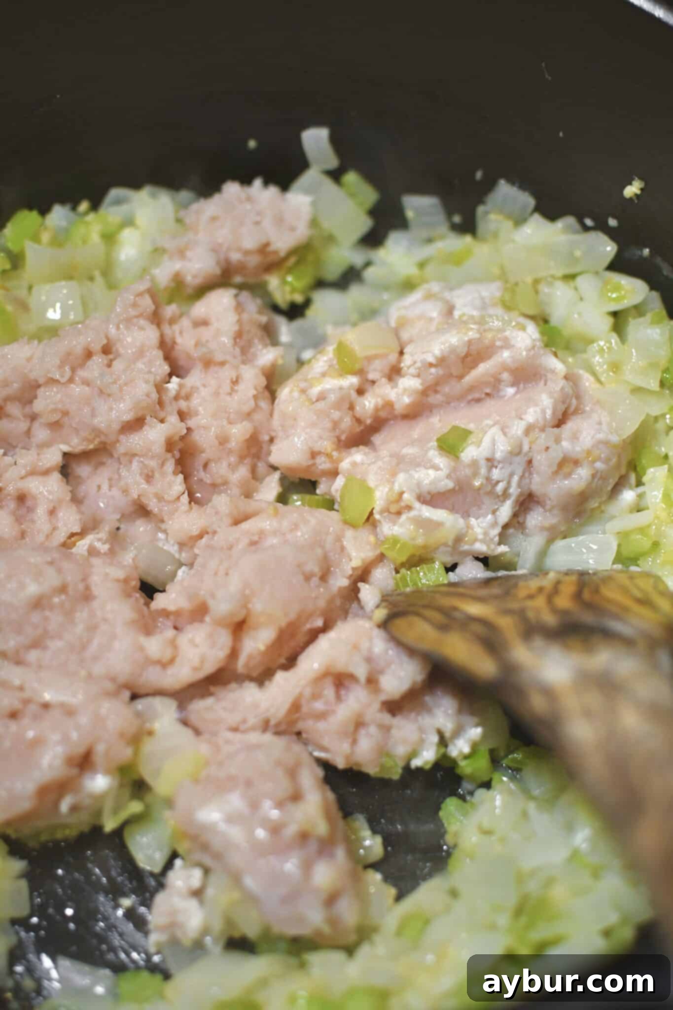 Minced chicken breast browning in the Dutch oven alongside sautéed vegetables.